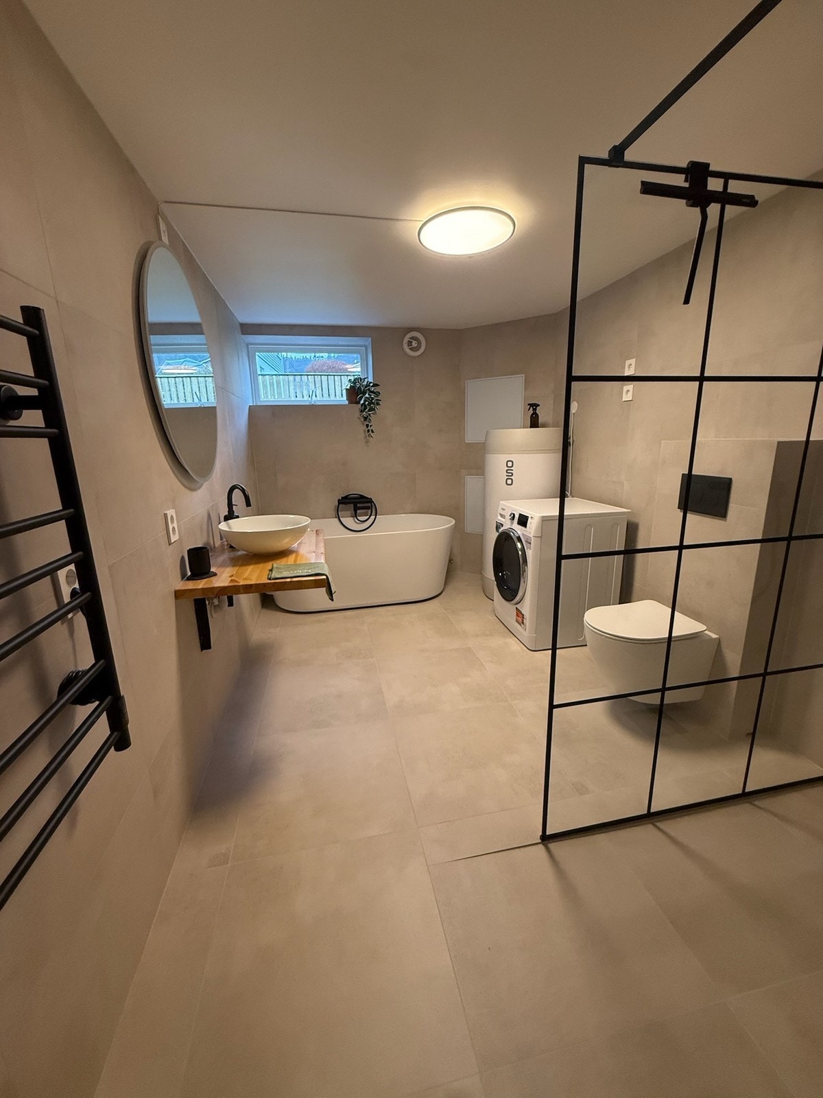 Badet er møblert med dusj, badekar, servant, speil, toalett, vaskemaskin og tørkestativ. Galleribilde