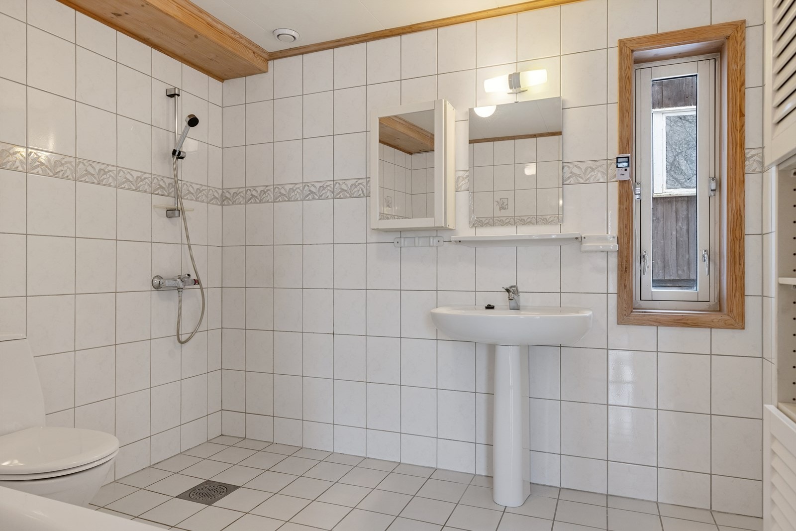 Badet fremstår som funksjonelt og velholdt fra byggeåret. Det er helfliset med varmekabler i gulvet og innredet med badekar, dusjhjørne, toalett, servant og vegghengt høyskap. Galleribilde