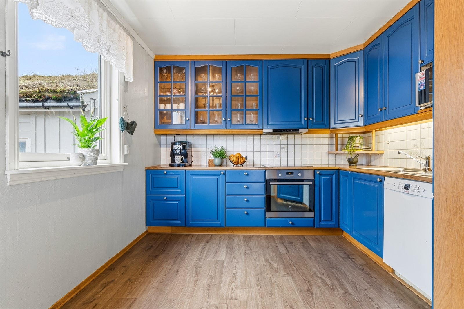 Kjøkkeninnredning med malte, profilerte fronter og takhøye overskap. Galleribilde