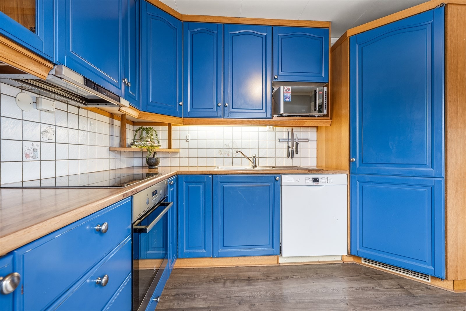 Integrert komfyr og mekanisk avtrekk gir en effektiv kjøkkenløsning. Godt med skap- og benkeplass. Galleribilde