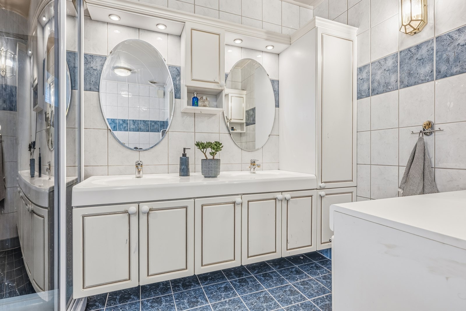 Flislagt bad med innredning med to nedfelte servanter, toalett, dusjkabinett og badekar. Elektriske varmekabler i gulv. Galleribilde