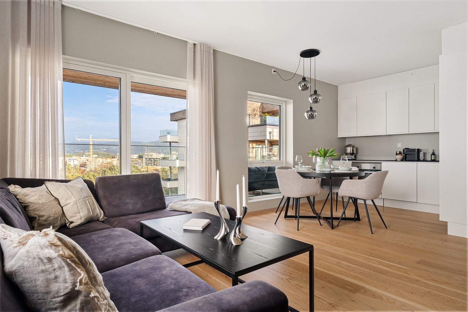 Åpen stue/kjøkken-løsning med delikate farger på overflatene og en nydelig enstavs eikeparkett på gulv. Galleribilde