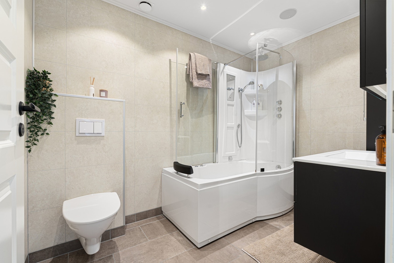 Vegghengt toalett, badekar med dusj og pen baderomsinnredning. Galleribilde