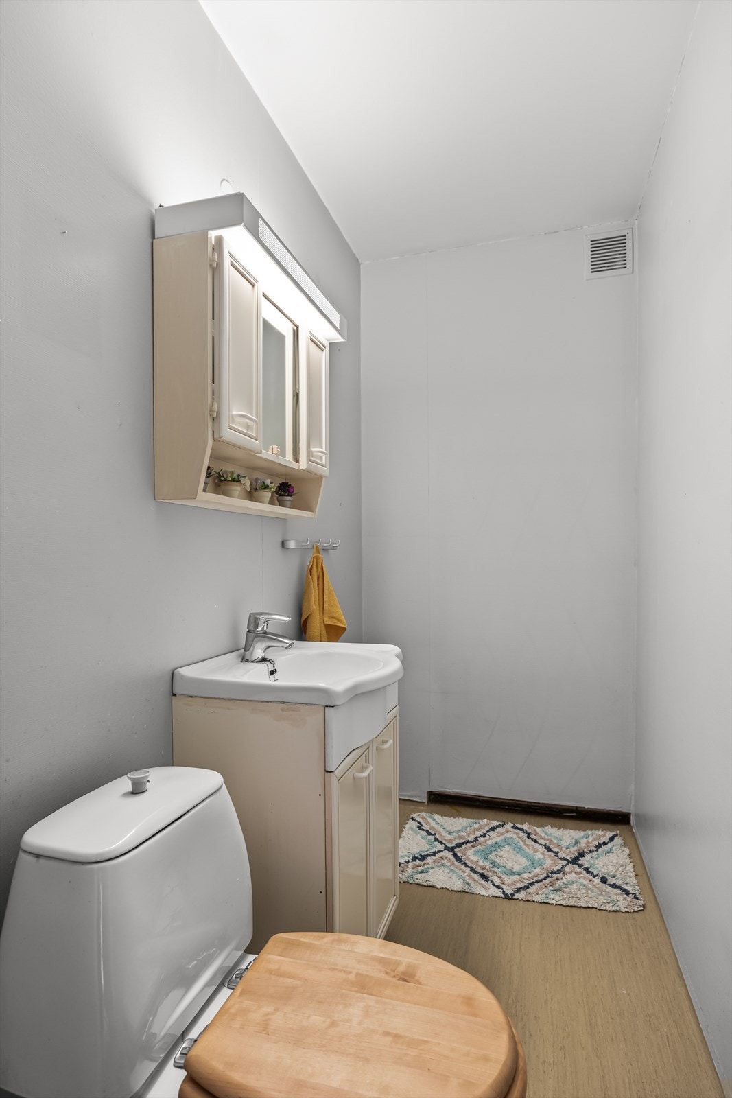 Bad med inngang fra entré. Rommet er innredet med servant med speil, skap og toalett. Gulv med vinyl og tapet på vegger gir et praktisk og funksjonelt rom. Galleribilde