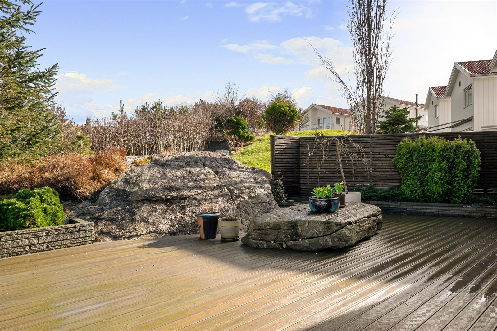 Flott opparbeidet tomt med platting, gjerde, blomsterbed og naturstein. Galleribilde