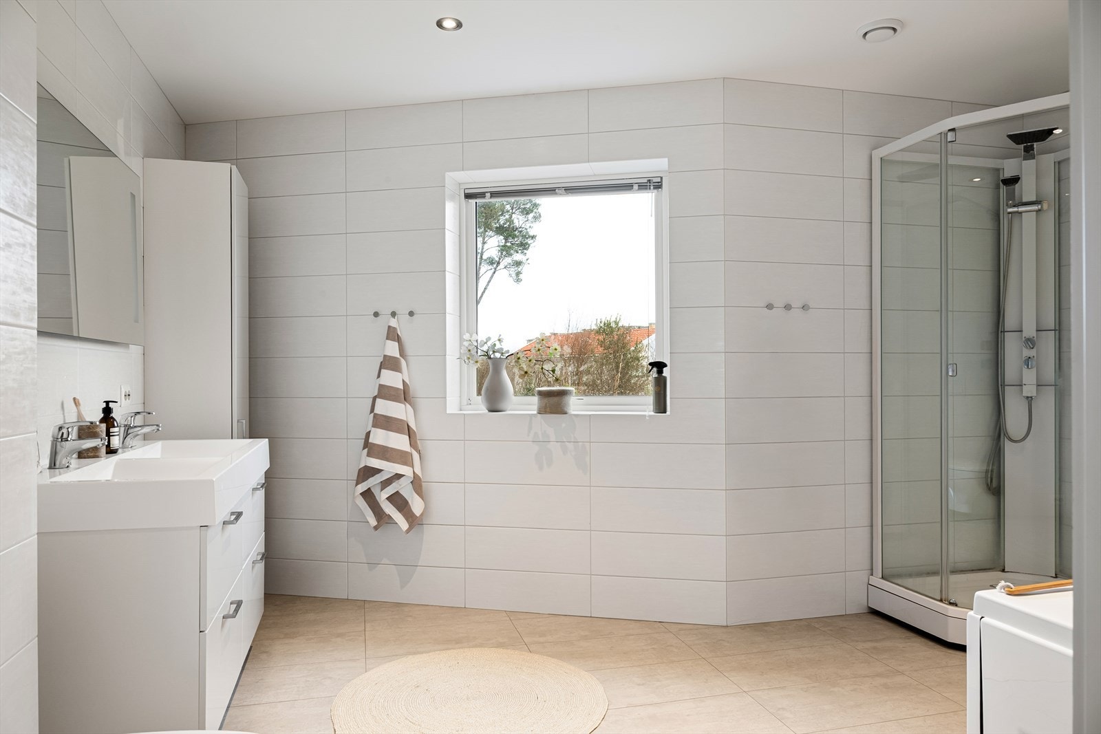 Badet er delikat innredet med badekar, dusjkabinett, vegghengt toalett, dobbel servant i seksjon og speil med belysning. Galleribilde