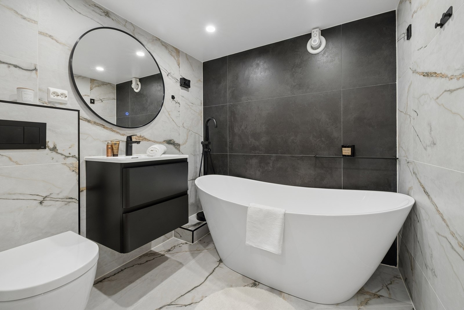 Pent flislagt bad med gulvvarme. Badet er innredet med servant, vegghengt toalett, badekar og baderomsinnredning med benkeskap med glatte fronter Galleribilde