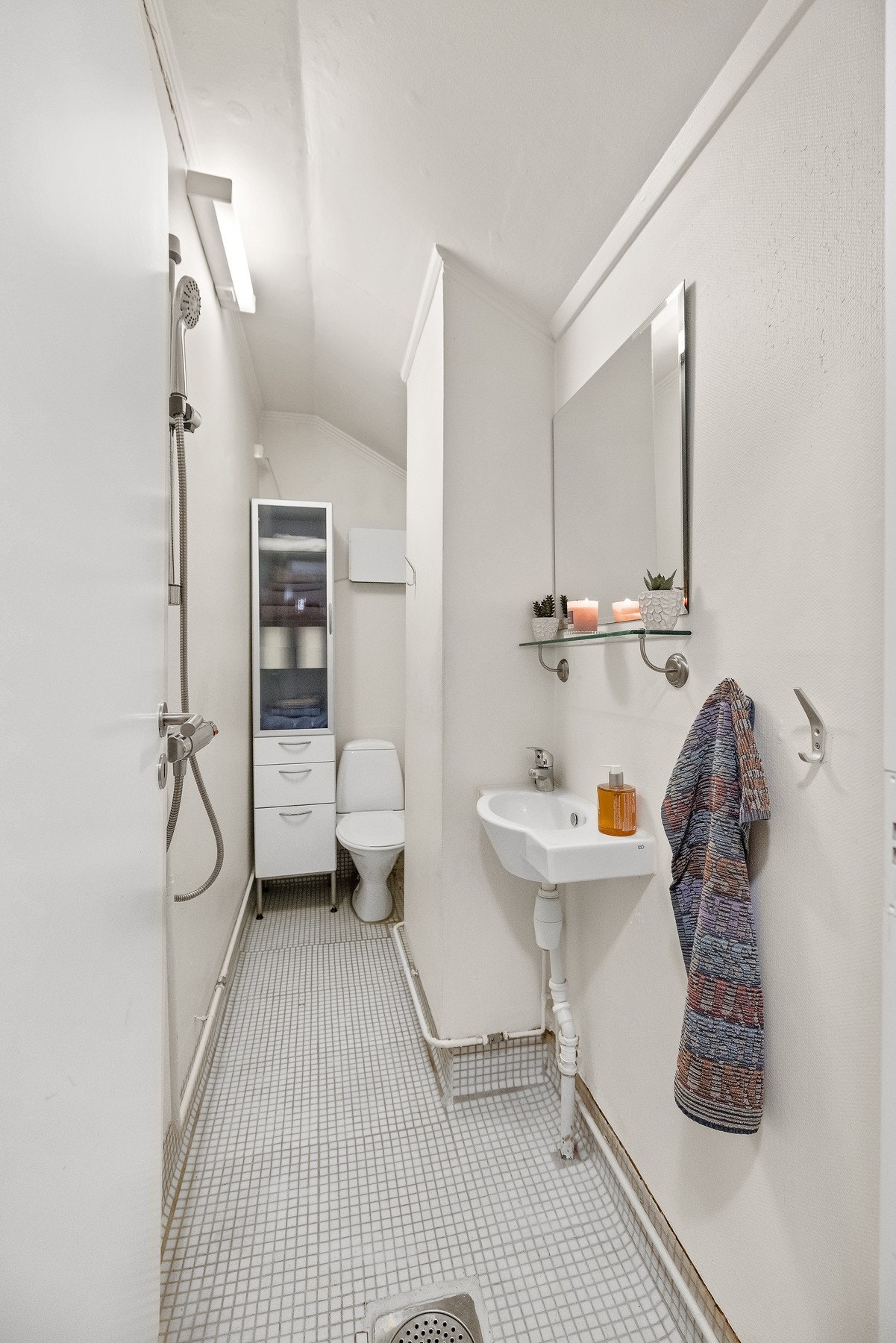 Badet har flislagt gulv og malte vegger. Baderommet er utstyrt med vegghengt servant med ett-greps armatur, vegghengt dusjarmatur og gulvstående toalett. Galleribilde