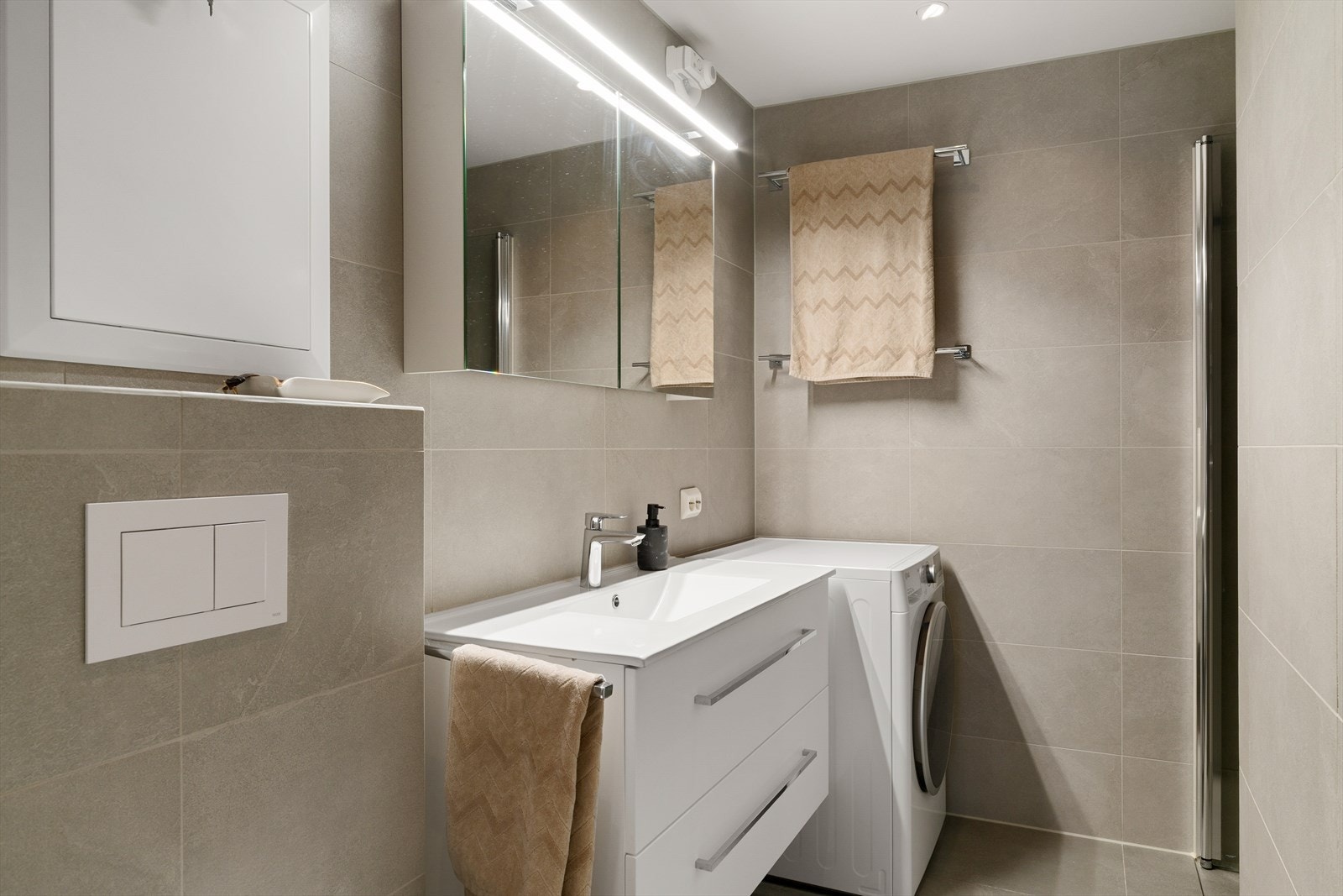 Badet har varmekabler på gulv, dusjsone og vegghengt servant. Galleribilde