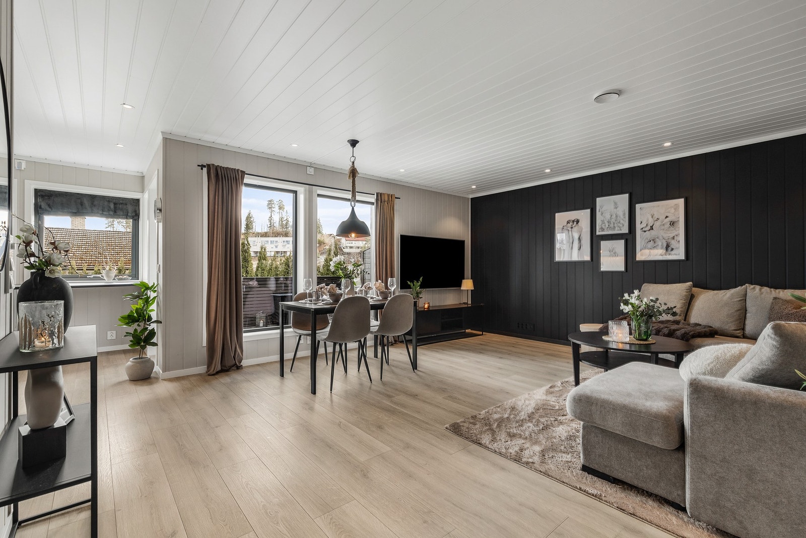 Lys og innbydende stue med 1-stavs laminat på gulv og panelplater på vegger og i himling Galleribilde