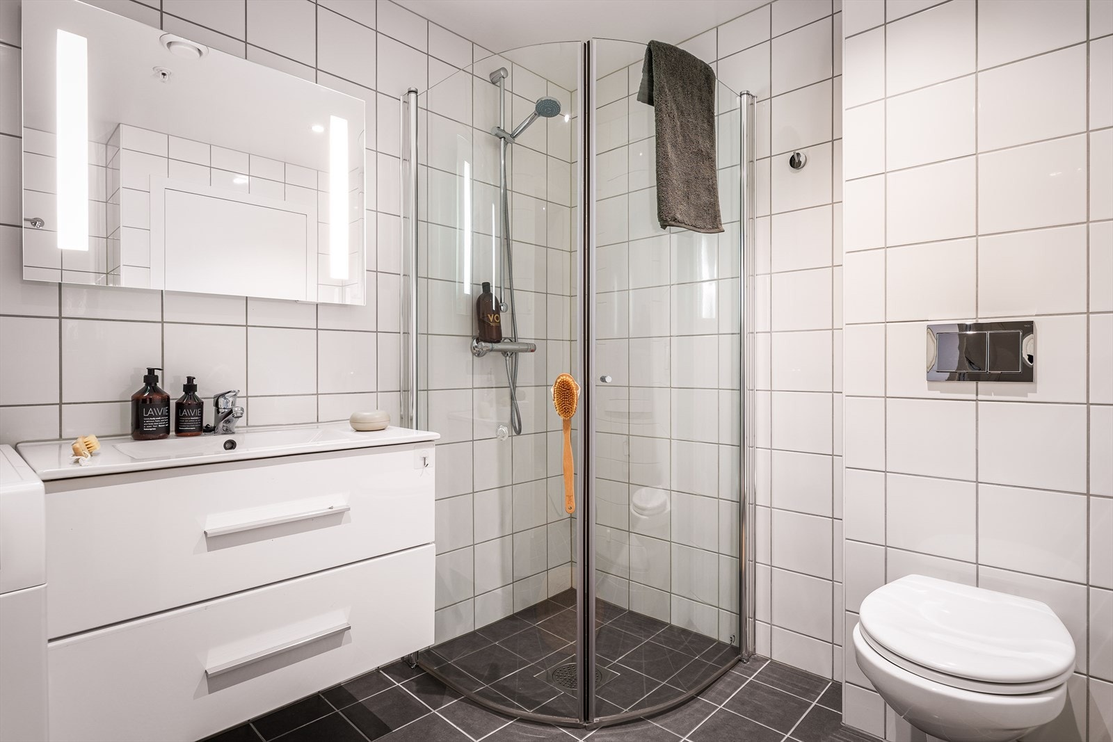 Badet har blitt innredet med servant med underskap, speil med belysning, vegghengt toalett og dusjnisje med innfellbare vegger. Galleribilde