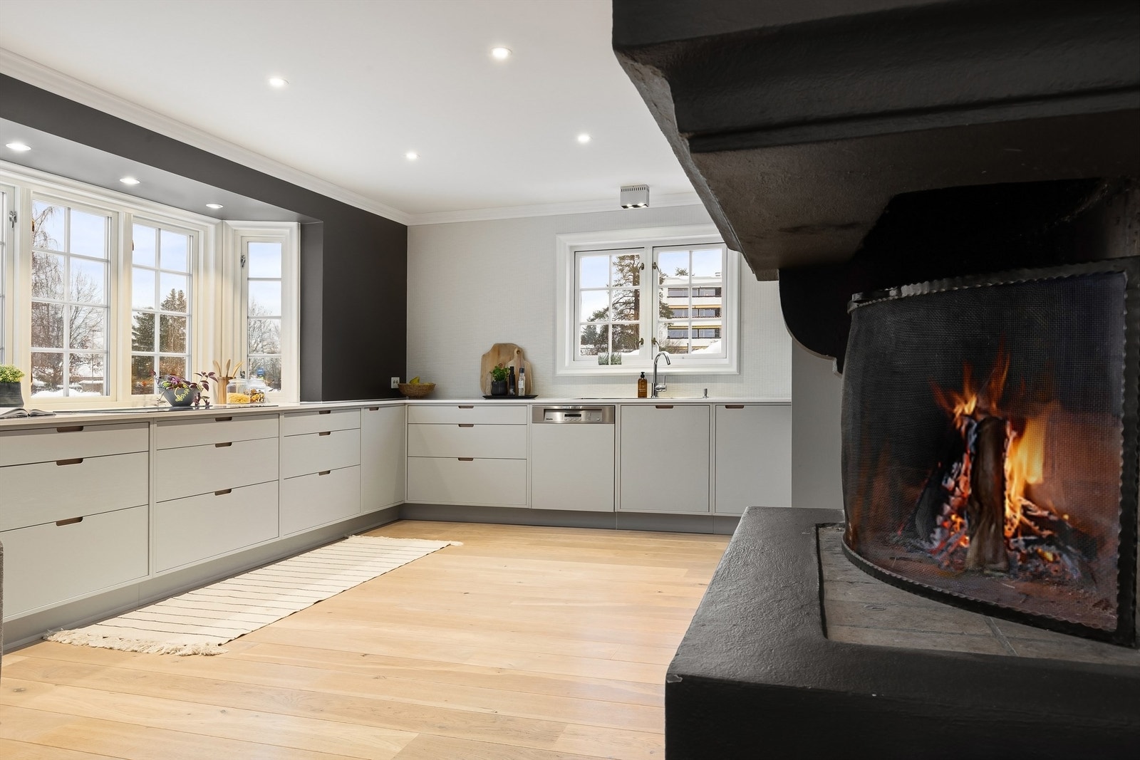 Østeråsen 5 er en stor enebolig over 3 plan og kan blant annet by på et stilrent kjøkken fra 2018 med koselig, åpen peis og plass for spisebord Galleribilde