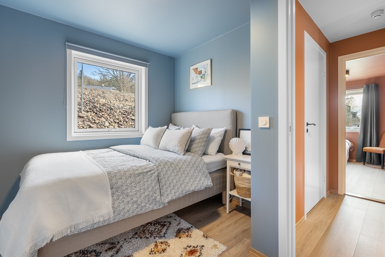 Lyst og innbydende soverom med rolige fargetoner og store vinduer som slipper inn naturlig lys. Galleribilde