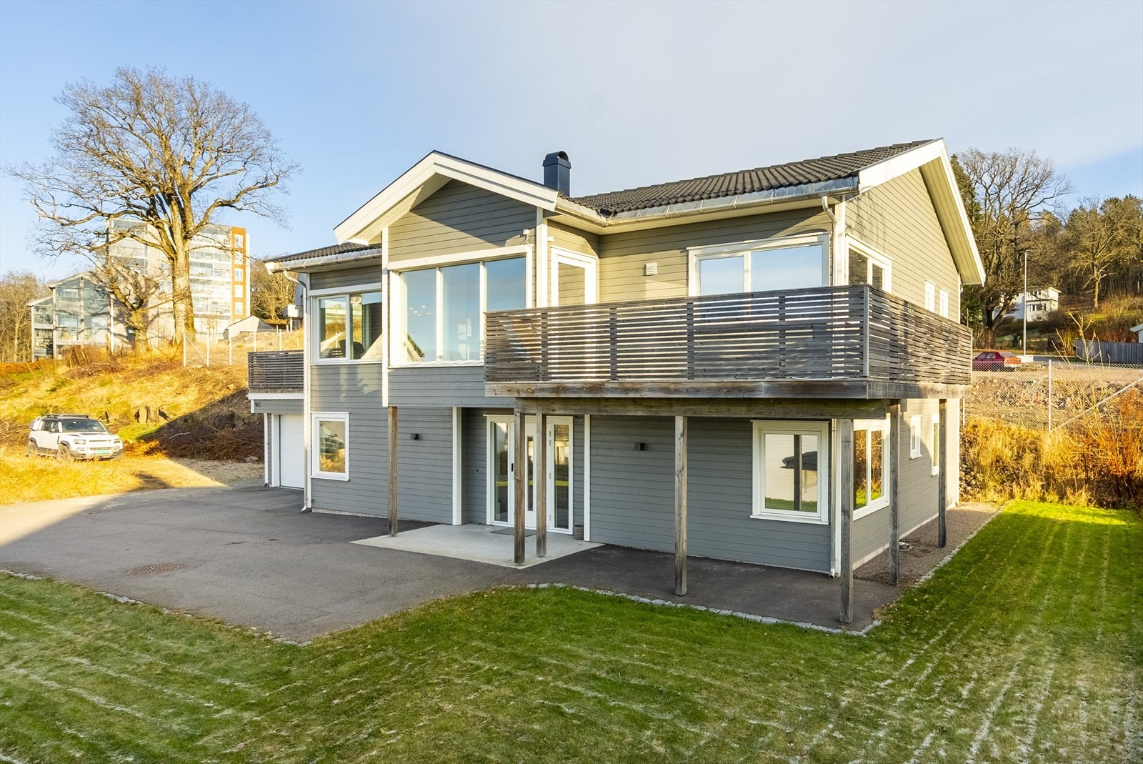 Velholdt hage og flott fasade med store vinduer og romslig terrasse over garasjen. Galleribilde