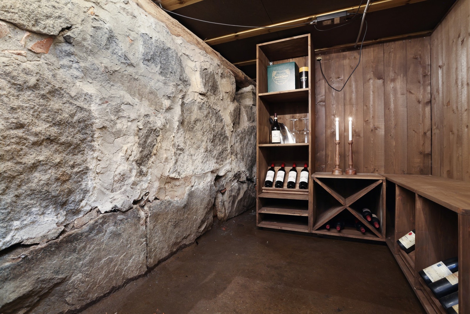 Vinkjeller under kjøkken med natursteinsvegger og trehyller for oppbevaring av vinflasker. Galleribilde