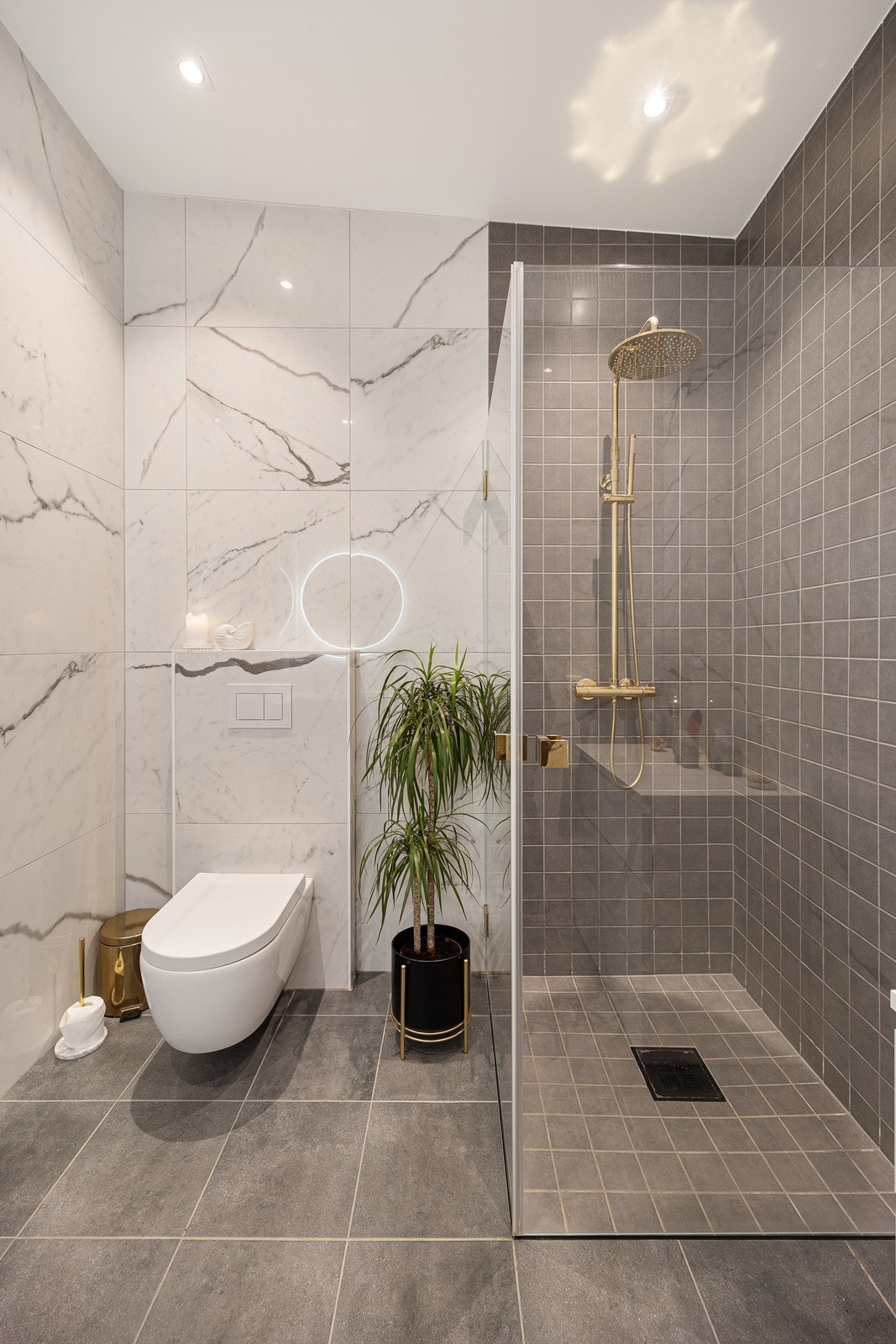 Badet har egghengt toalett, opplegg for vaskemaskin og et dusjhjørne med regnfallsdusj og innfellbare glassdører. Galleribilde