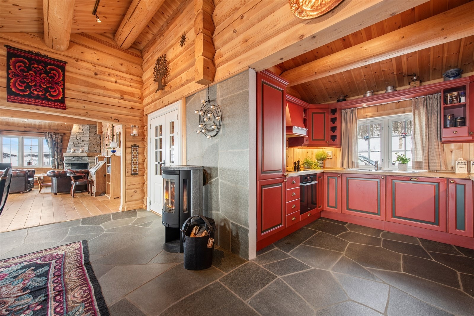 En effektiv vedovn ved kjøkkenet gir ekstra varme og hygge, i tillegg til den åpne peisen i stuen. Galleribilde