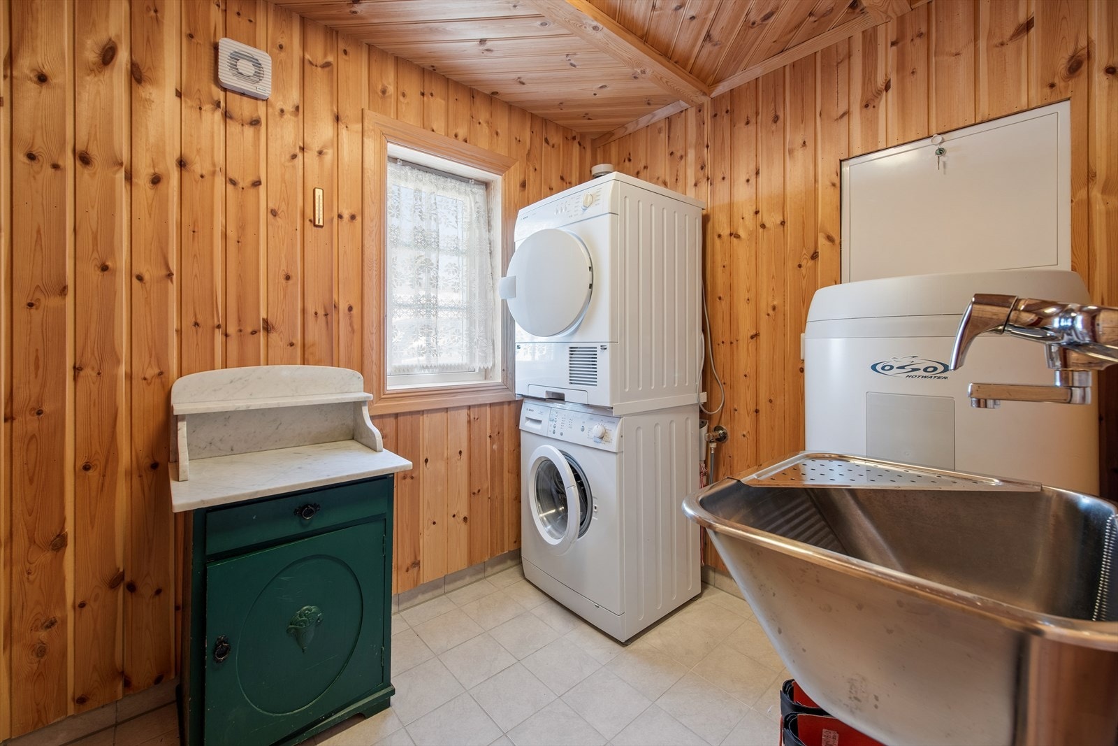 Praktisk vaskerom med opplegg for vaskemaskin, utslagsvask og en varmtvannsbereder på ca. 200 liter. Rommet har egen inngang, noe som gir enkel tilgang uten å gå gjennom resten av hytten. Galleribilde