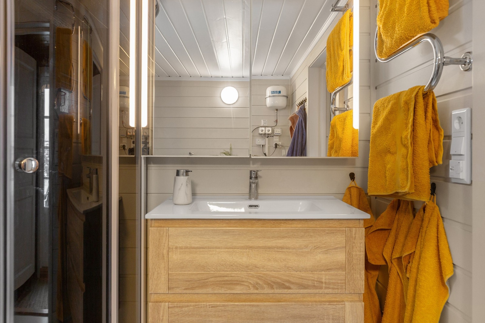 Badet har fliser på gulv med varmekabler, og trepanel på vegg. Galleribilde