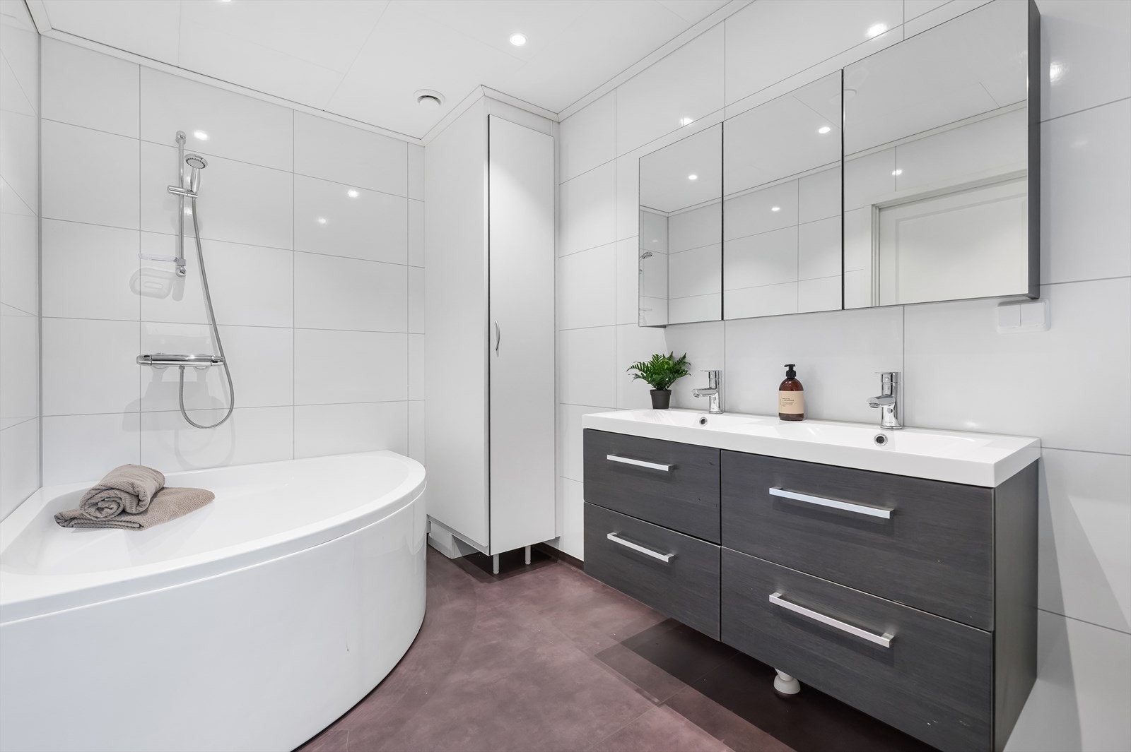 Badet ved soverommene er romslig og inneholder innredning med to servanter, speilskap, toalett og badekar. Galleribilde