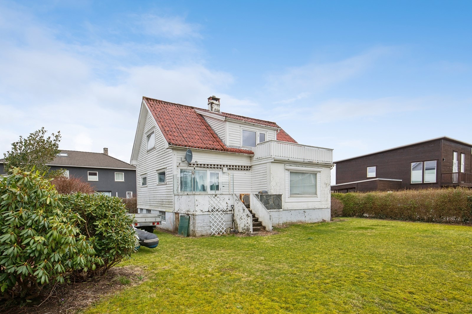 Tomten er pent opparbeidet med en tilnærmet flat hage, innrammet av hekk som er pent beplantet med ulike vekster. Galleribilde