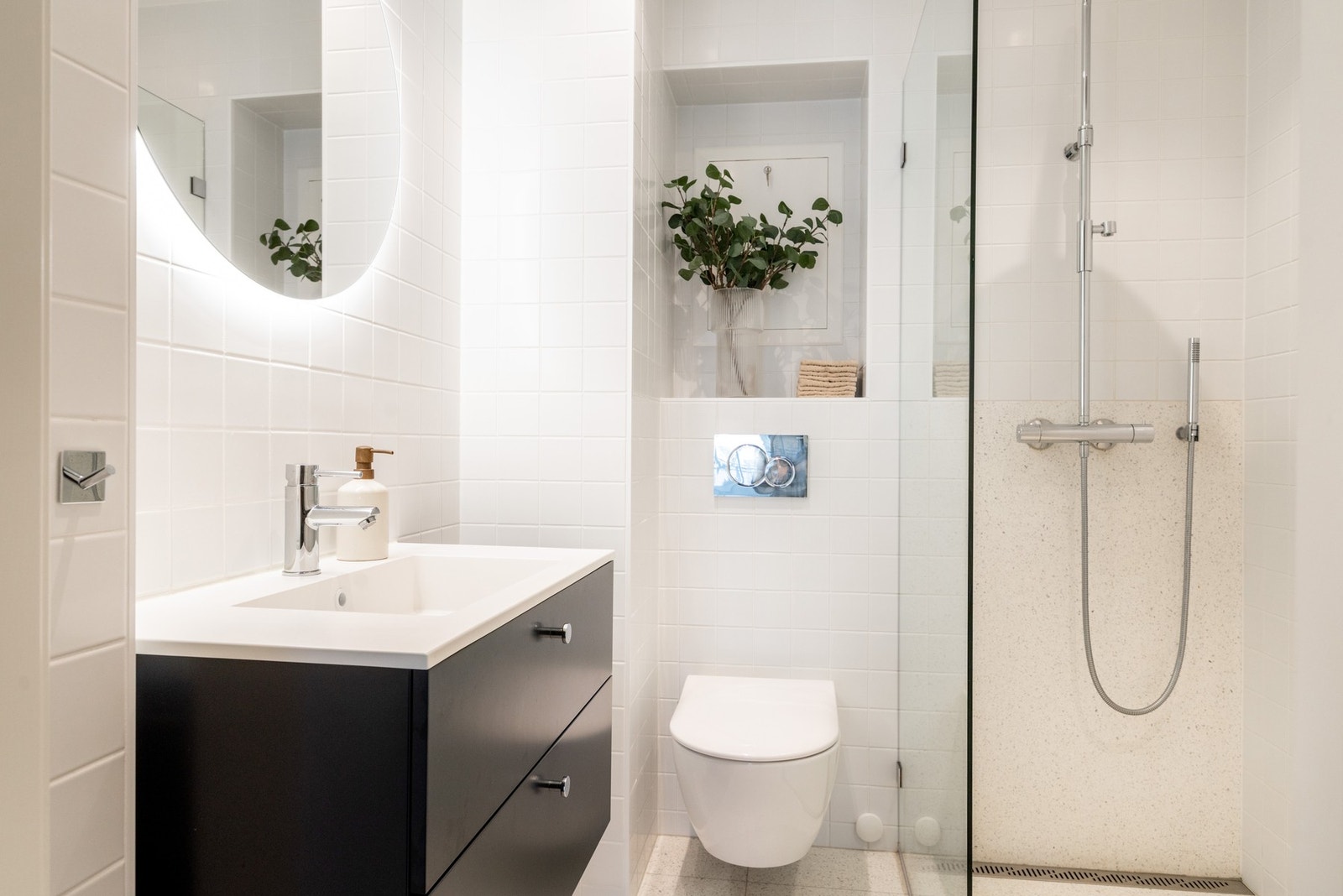 Badet fremstår som moderne og stilrent med lyse flislagte overflater. Her er det ekte italienske terrazzofliser fra SKOGR på gulvet og i dusjsonen. Galleribilde