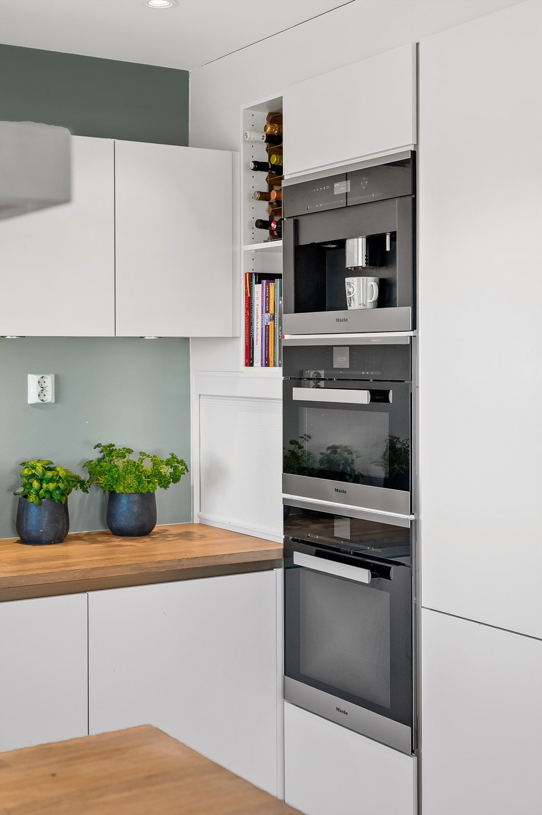 Her får du hvite glatte fronter, benkeplate i eik og integrerte hvitevarer fra Miele med koketopp, stekeovn, microbølgovn, kaffemaskin, oppvaskmaskin og kjøleskap med frysedel. Galleribilde
