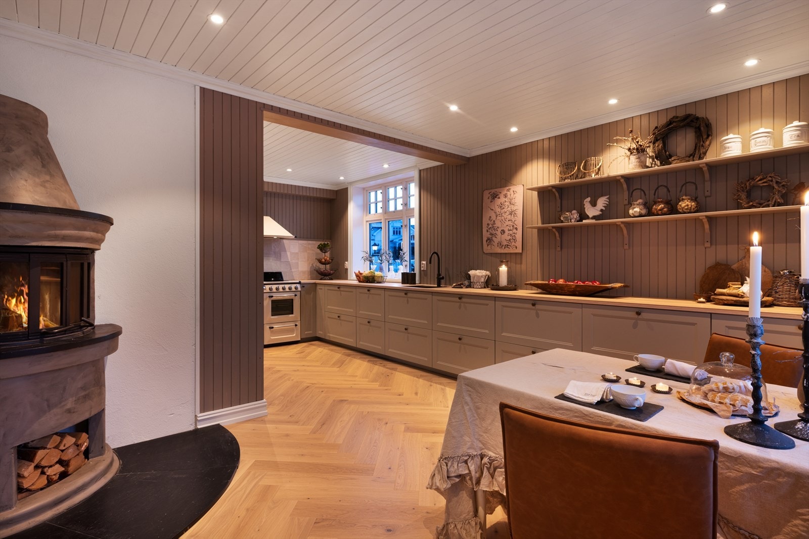 Stor, rund peis med glassinnsyn og vednisje gir både varme og en koselig atmosfære i rommet. Galleribilde