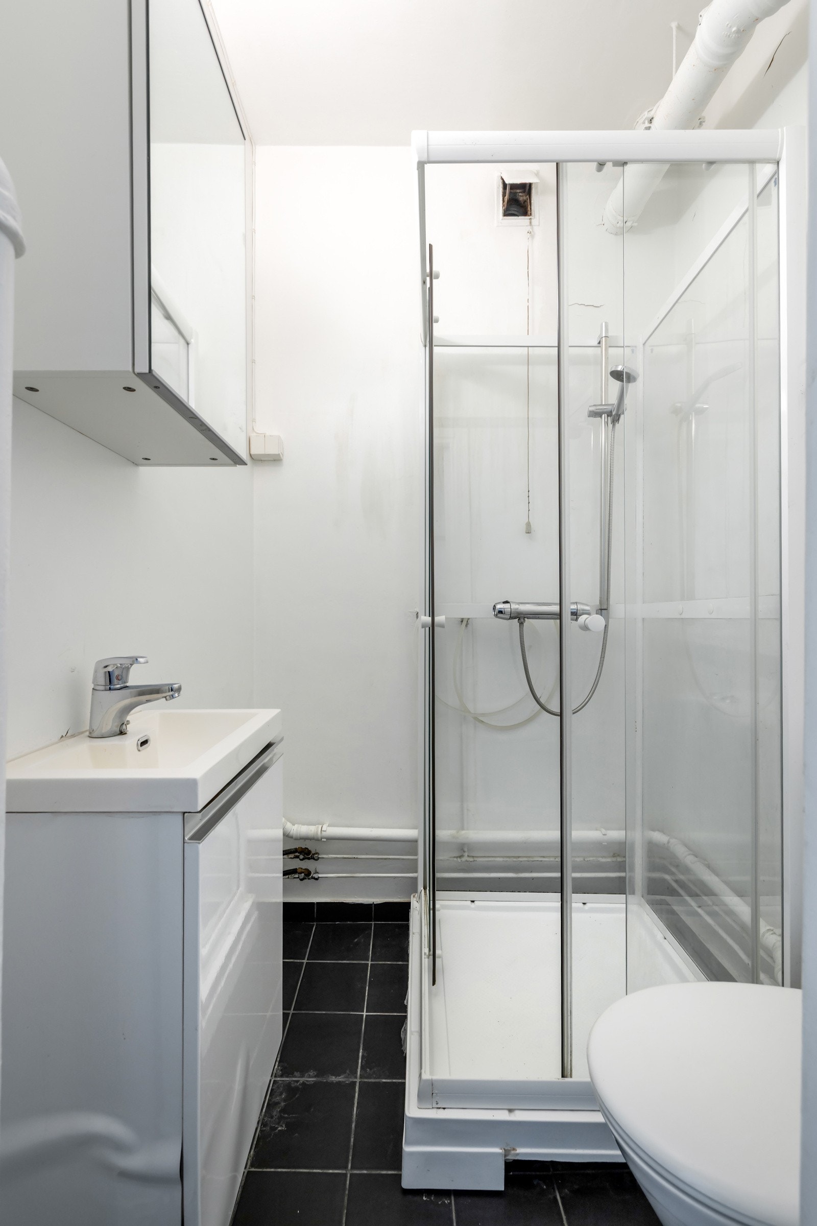 Badet er flislagt og har dusjkabinett, toalett, servantinnredning og speilskap - Badet har moderniseringbehov Galleribilde