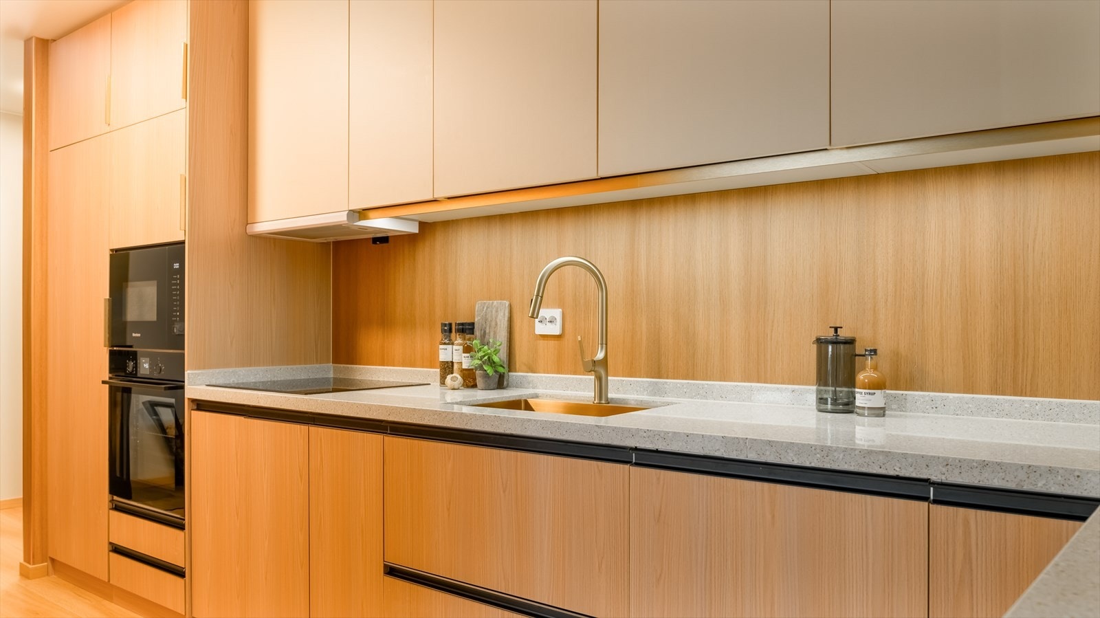 Kjøkkenet er stilrent innredet med en kombinasjon av trefargede og lyse, slette fronter og grå benkeplate i eksklusiv kompositt. Et stort og godt kjøkken hvor man har rikelig med skap- og skuffeplass, samt gode arbeidsflater på benk. Galleribilde