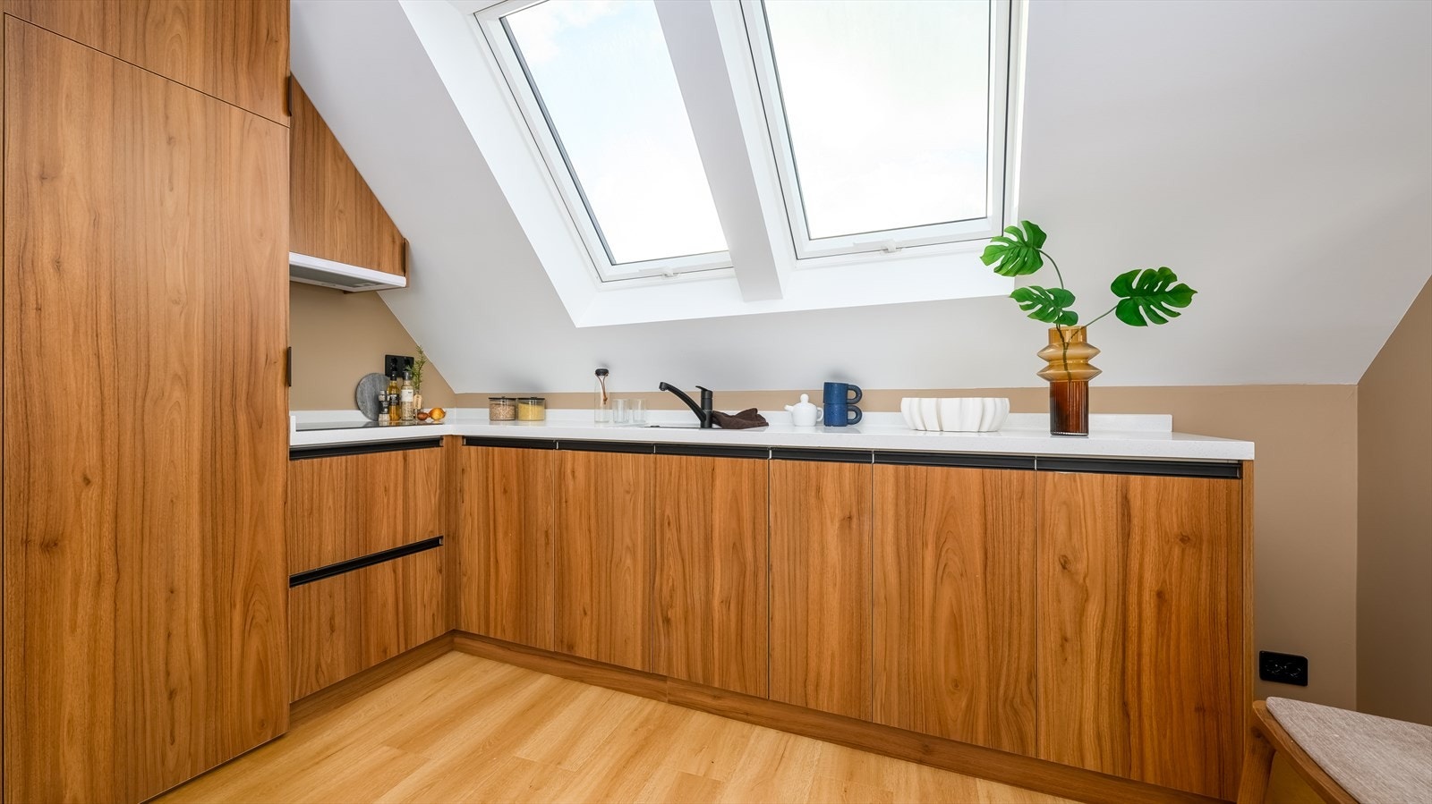 Stue og kjøkken ligger i åpen løsning. Kjøkkenet er lekkert innredet med trefargede, slette fronter og en hvit, solid benkeplate i kompositt. Et godt utnyttet kjøkken som er tilpasset skråtaket og gir godt med benkeplass. Galleribilde