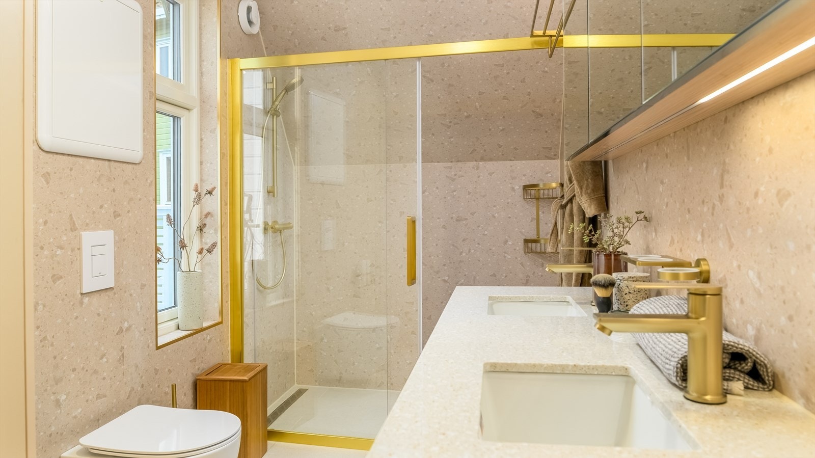 Badet er lekkert innredet med store, lyse fliser på gulvet og gråbeige baderomsplater på vegg. I gulvet har man også varmekabler for ekstra komfort. Galleribilde