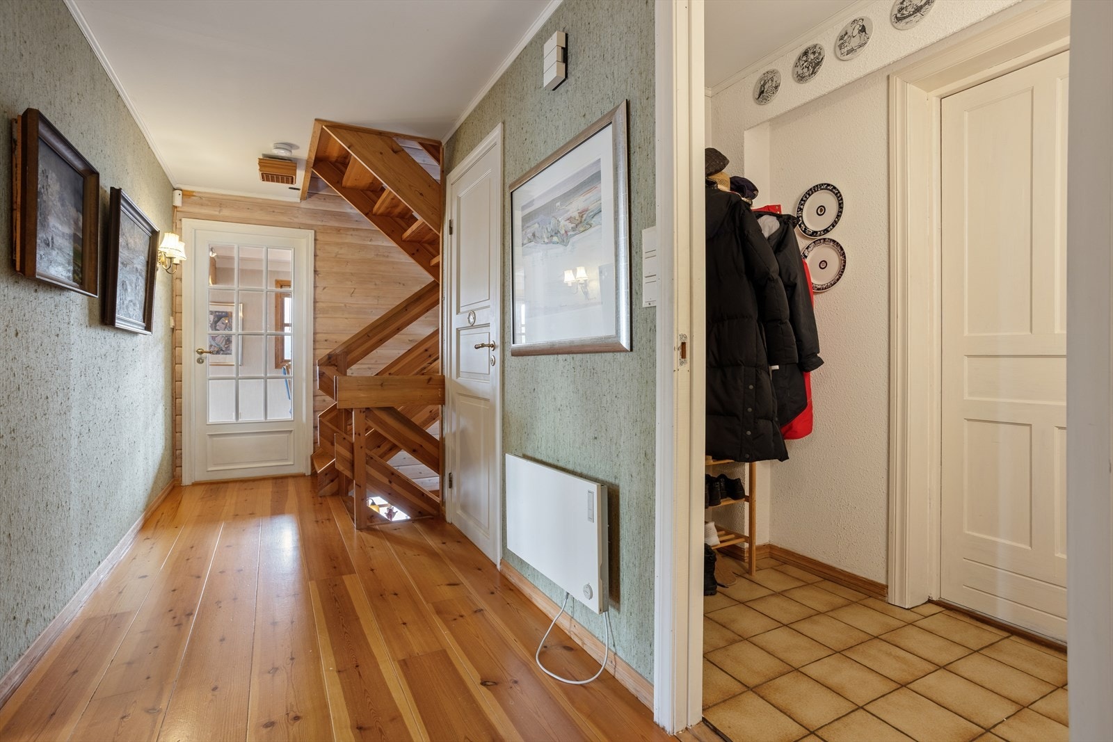 Romslig gang med plass til oppbevaring. Den innvendige trappen i heltre forbinder boligens tre plan. Galleribilde