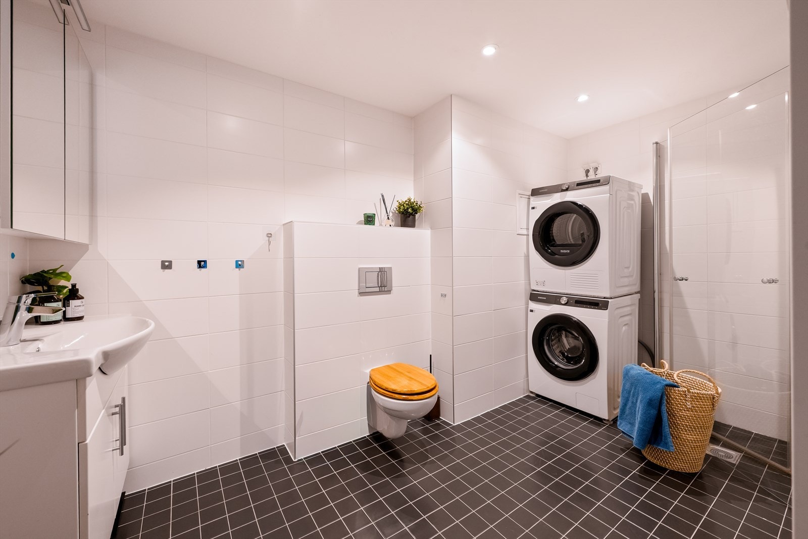 Badet er innredet med servant, vegghengt toalett, dusjhjørne samt opplegg for vaskemaskin og tørketrommel. Galleribilde