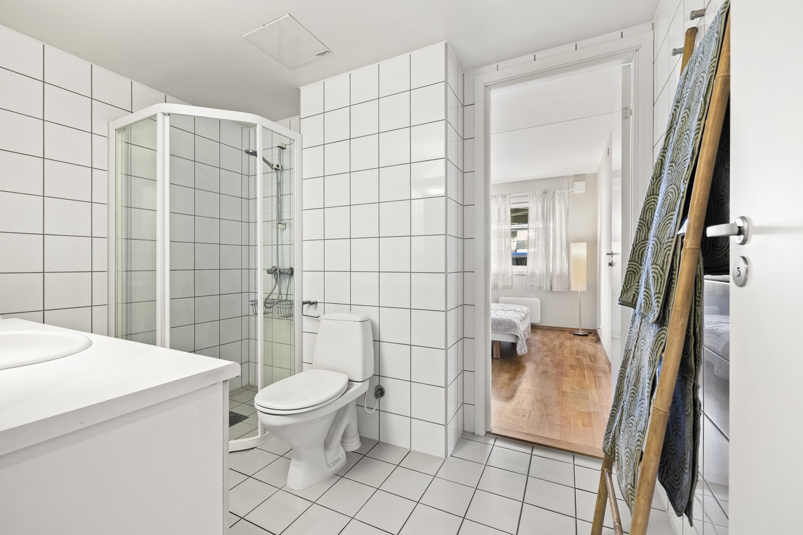Badet er innredet med servant, toalett og et dusjhjørne med innfellbare vegger. Det er inngang til badet fra to sider. Galleribilde