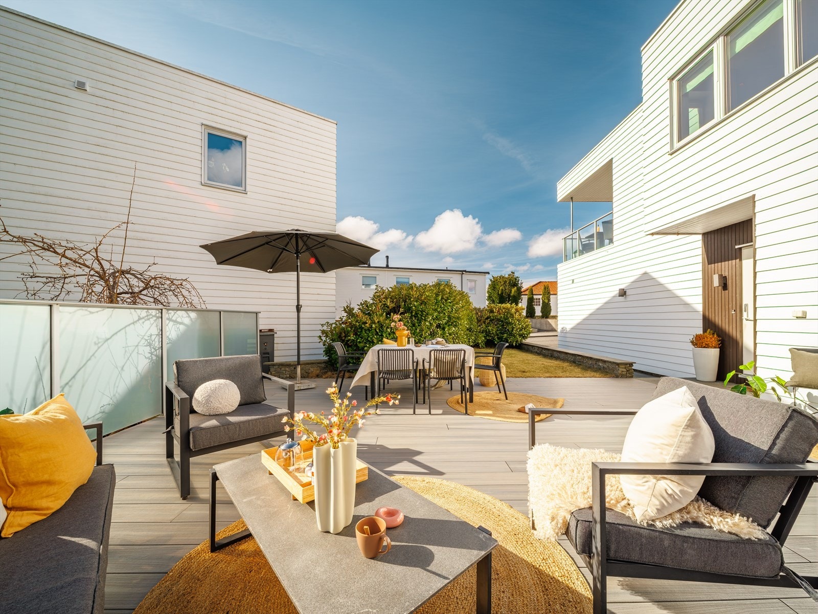 Terrassen har rekkverk av glass og metall. Tomten er ellers pent opparbeidet med plen, hekk og asfaltert tun. Galleribilde