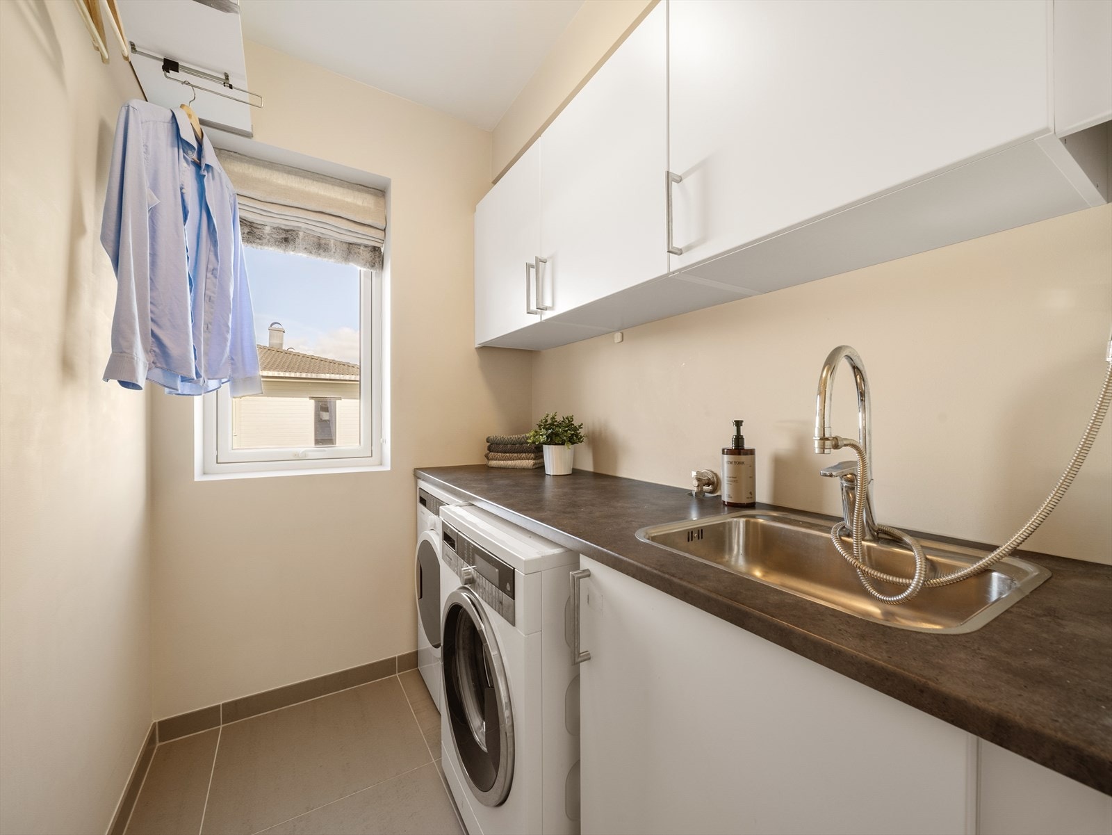 Videre inneholder etasjen et praktisk vaskerom med flislagt gulv og gulvvarme. Rommet er innredet med stålvask, benkeplate, skapinnredning, samt opplegg for vaskemaskin og plass til tørketrommel. Galleribilde