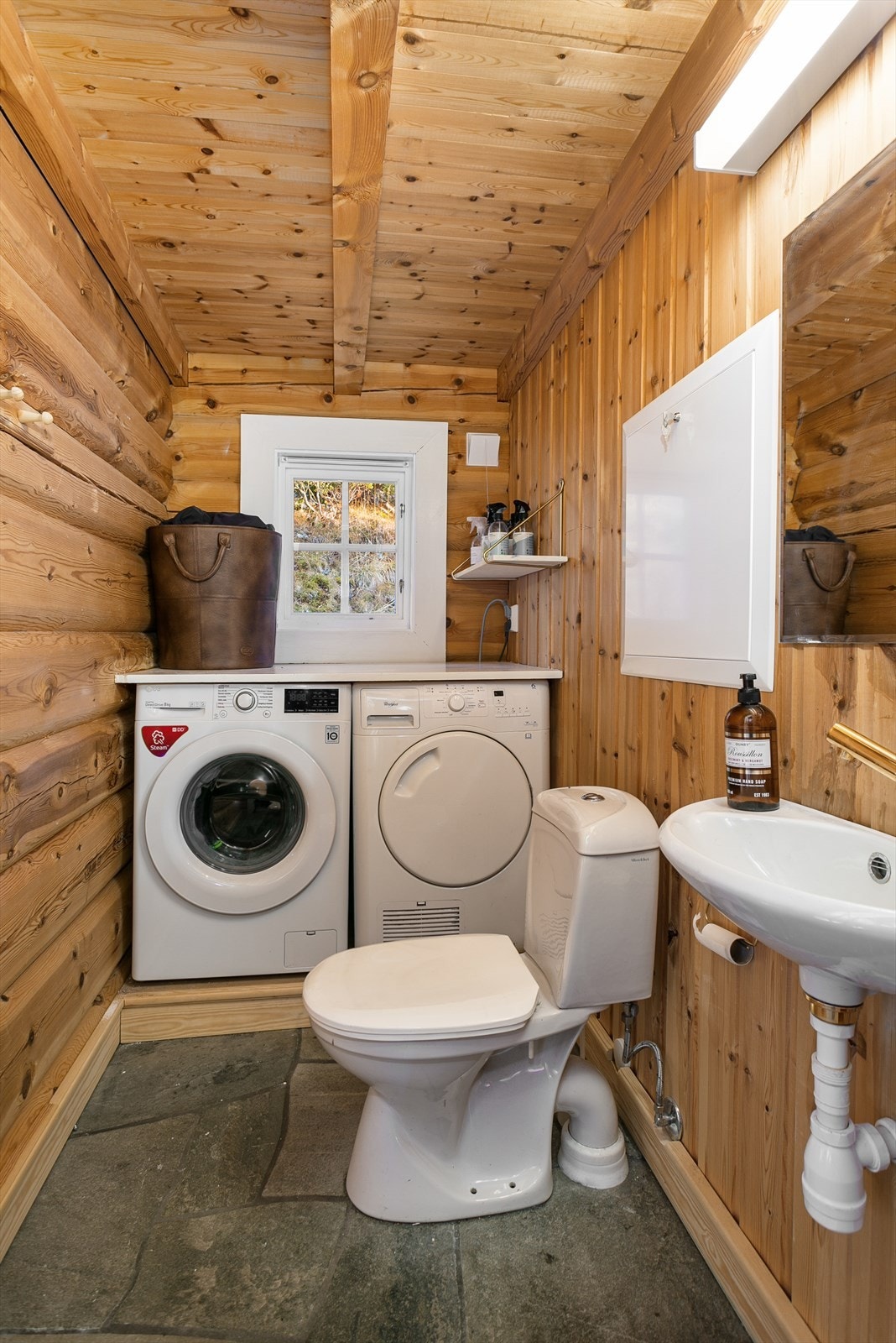 Vegg i vegg med badet ligger et praktisk vaskerom med opplegg for vaskemaskin og tørketrommel, samt ekstra toalett. Galleribilde