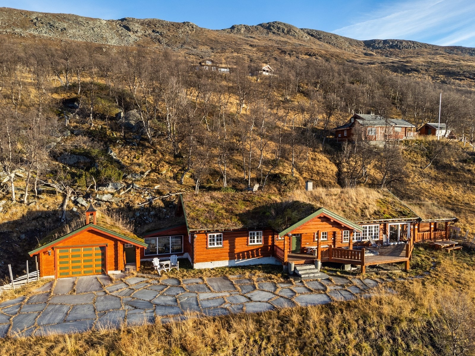 Gårdsplassen er pent opparbeidet med store skiferheller. Garasjen på ca. 25 kvm ble oppført i 2008 og har elektrisk portåpner. Det er god plass til både bil og oppbevaring. Det er også en egen parkeringsplass nede ved veien. Galleribilde