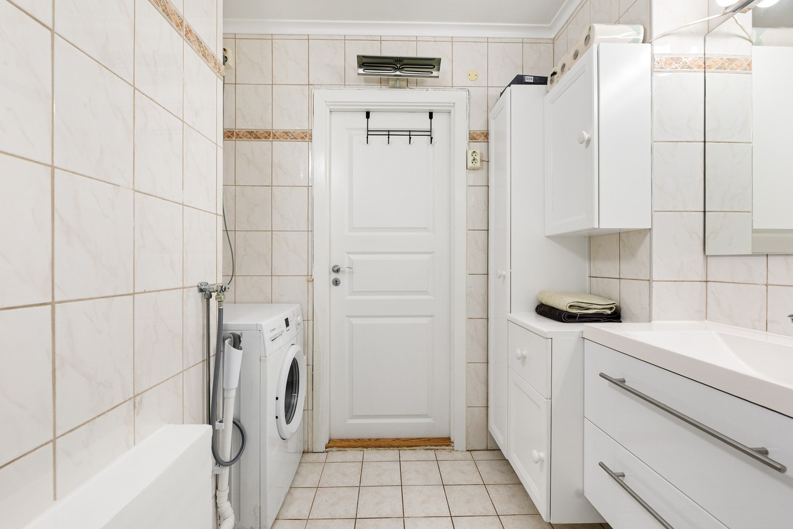 På det flislagte badet er det baderomsinnredning med servant, div. skap, gulvstående wc, dusjkabinett og opplegg for vaskemaskin Galleribilde