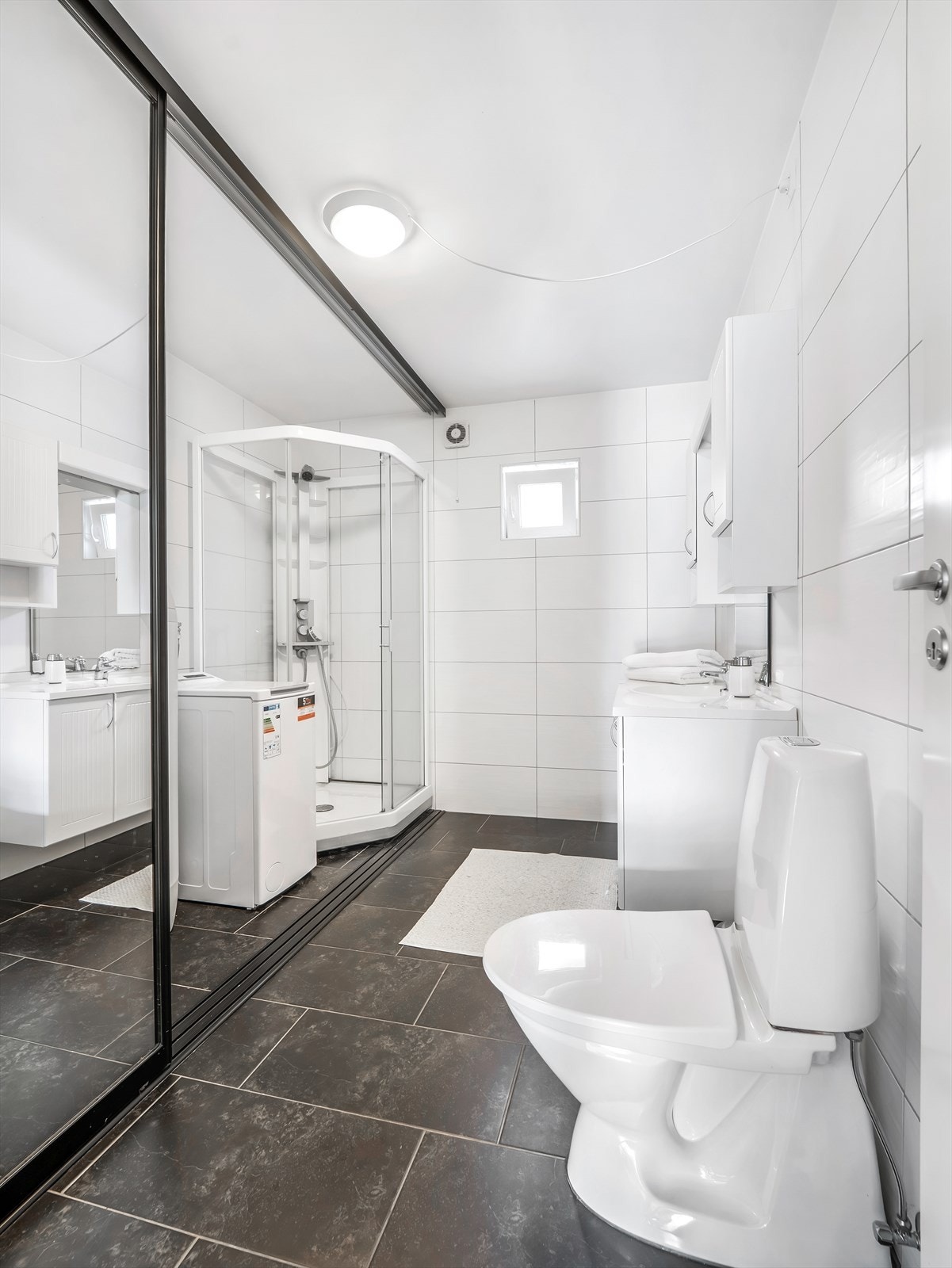 På badet har man en praktisk løsning med skyvedør som kan lukkes for å skjule dusj og vaskemaskin Galleribilde