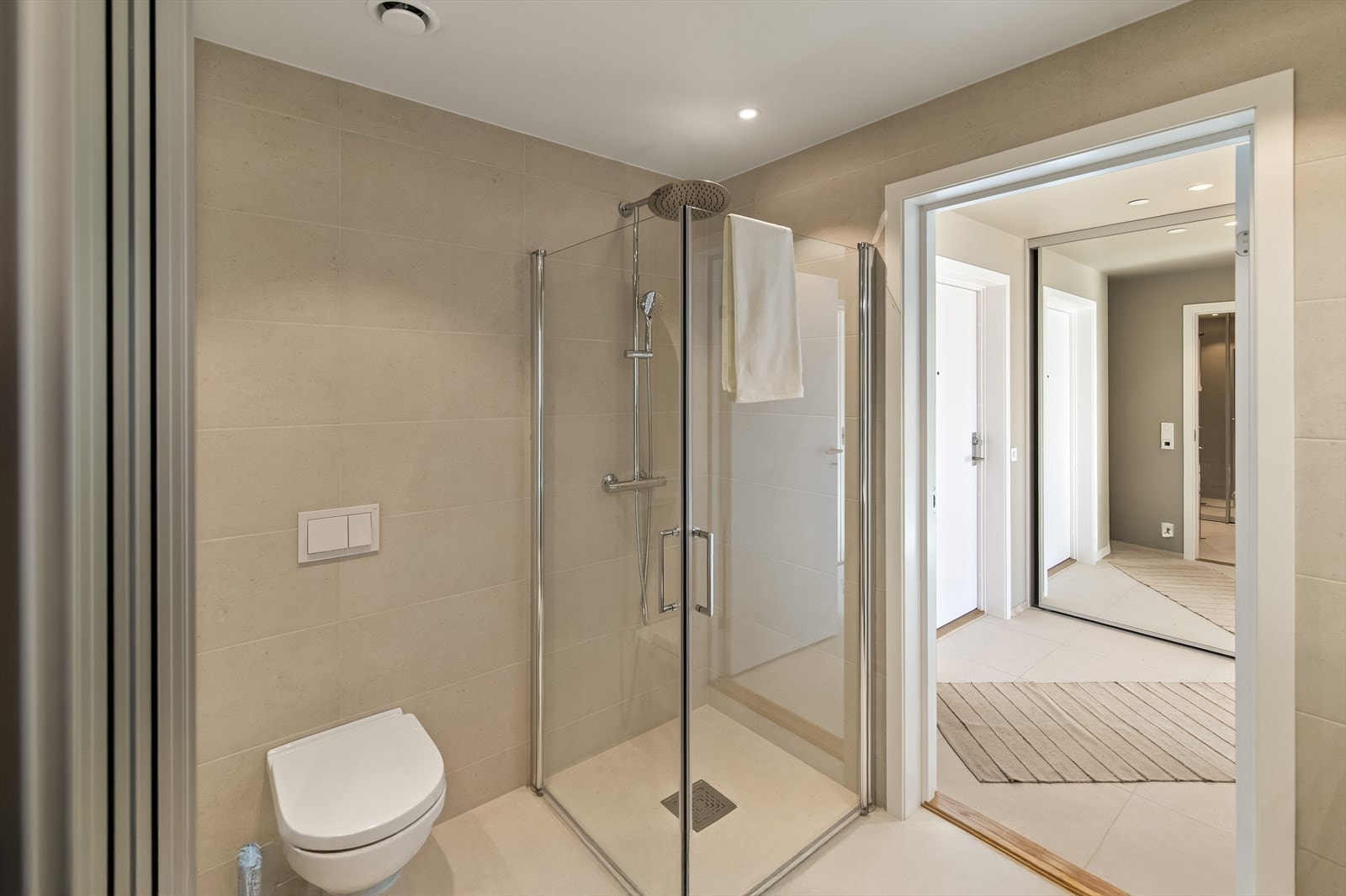Begge badene har en toppmoderne finish med store, lys beige vegg- og gulvfliser. Varme er lagt i gulvet, og de har downlights og vegghengt toalett. Galleribilde