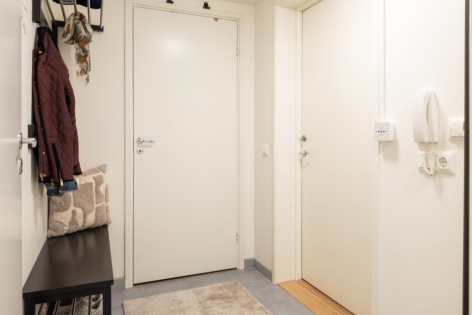 Flislagt inngangsparti med plass til å henge av seg yttertøy og sko. Galleribilde