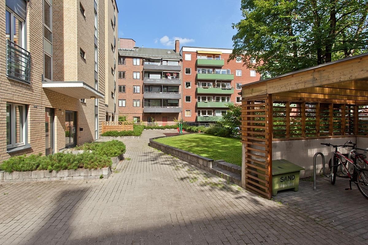 Pent fellesområde med sitteplasser, sykkelparkering og grøntareal. Galleribilde