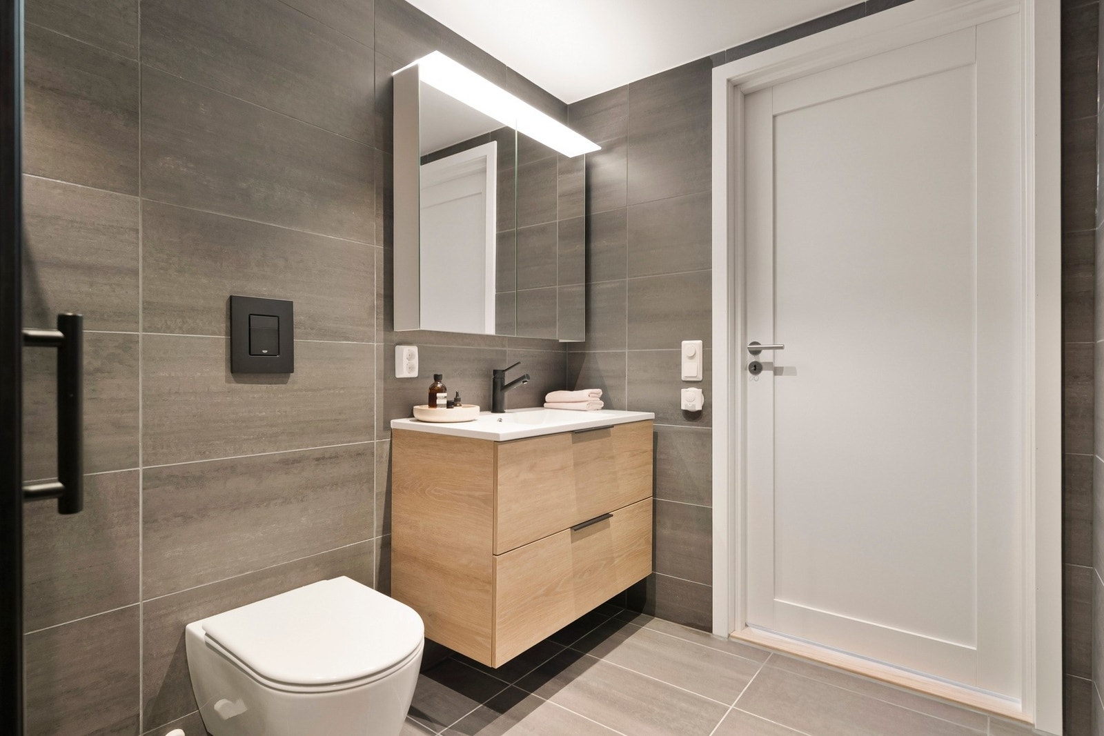Badet er innredet med vegghengt toalett, servant med skuffer under og dusjhjørne med innfellbare glassdører og regnfallsdusj. Det er opplegg for vaskemaskin/tørketrommel. Galleribilde