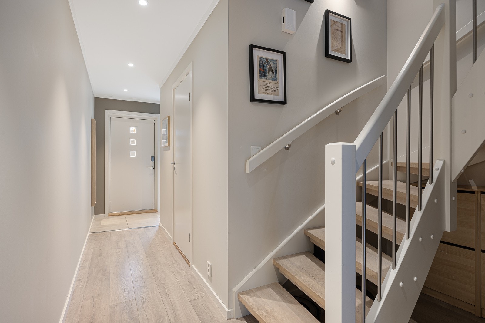 Videre innover i gangen er det enstavs laminatgulv, downlights og eiketrapp opp til andre etasje Galleribilde