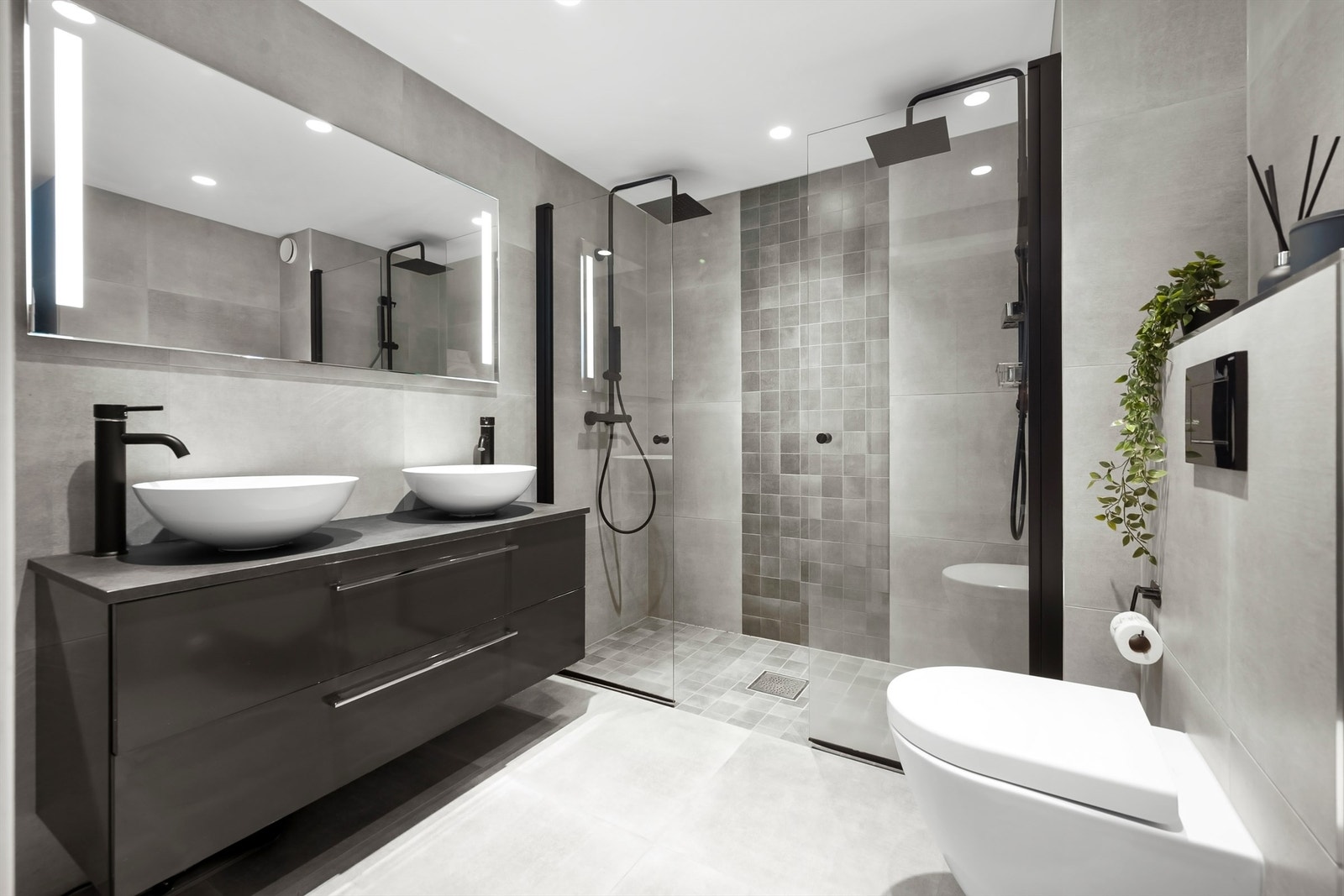 Moderne, flislagt bad med gulvvarme og en bred servantinnredning med to servanter. Galleribilde