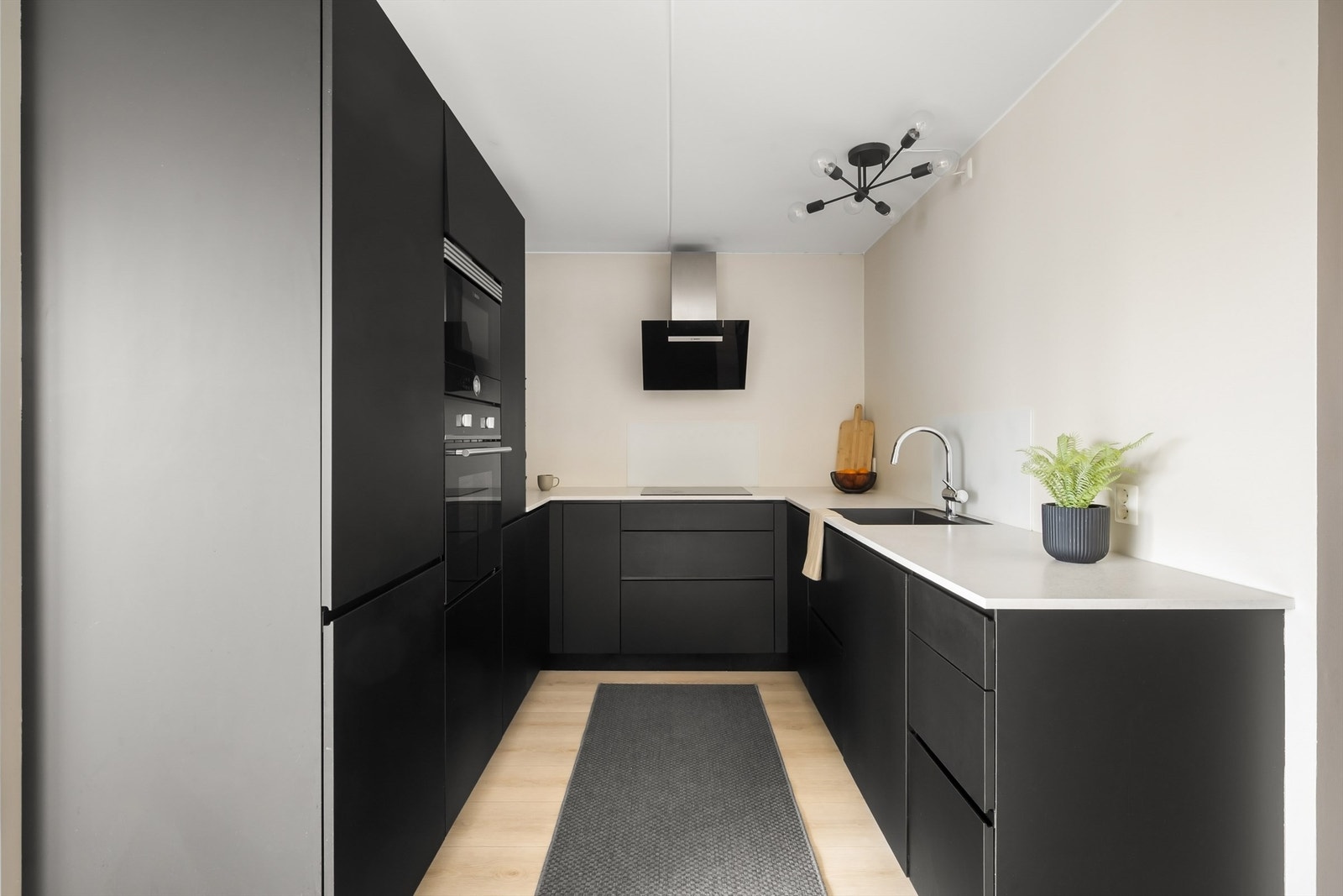 Kjøkkenet har en stilren innredning med mørke, slette fronter og alle hvitevarer integrert. Galleribilde