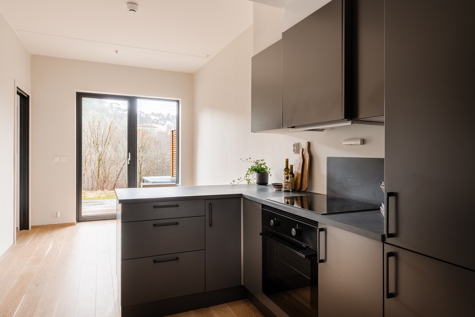 Kjøkkenet er stilrent og funksjonelt, med glatte skapfronter og en laminat benkeplate Galleribilde