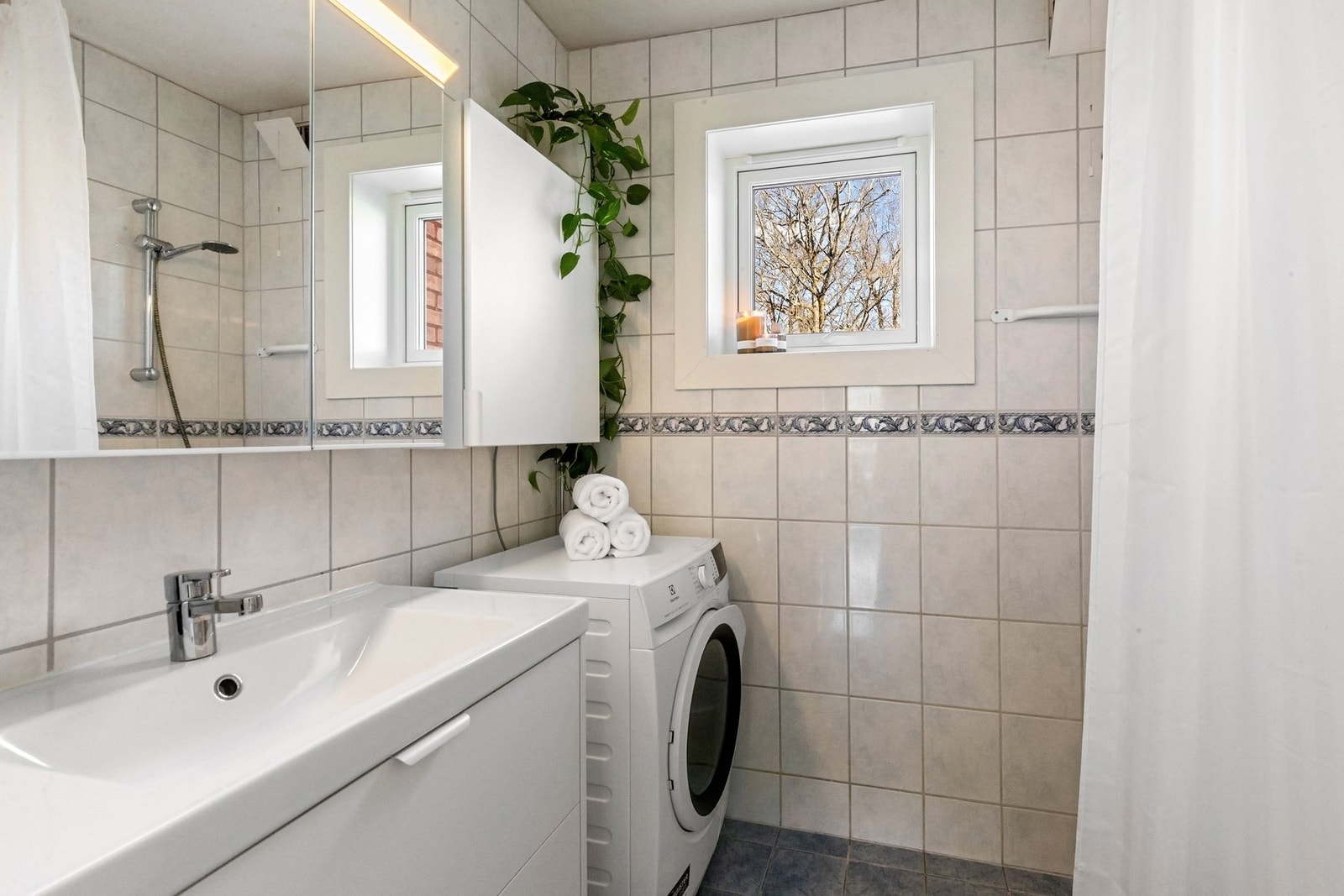 Baderommet er praktisk utformet med stort servantskap med heldekkende servant, speilskap med lysarmatur, opplegg for vaskemaskin og dusjsone. Borettslagets beboere disponerer også fellesvaskeri ved behov Galleribilde